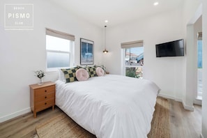 Quarto com cama grande, mesa de cabeceira, televisão e janela com vista.