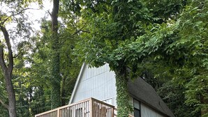Ein Haus mit einer Holzterrasse und einer Treppe, die zu einer zweiten Ebene führt.