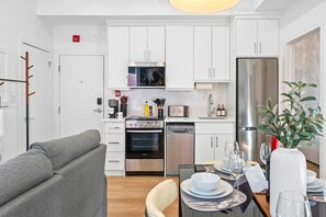 A modern kitchen with white cabinets, a stainless steel refrigerator, an oven, and a dishwasher.