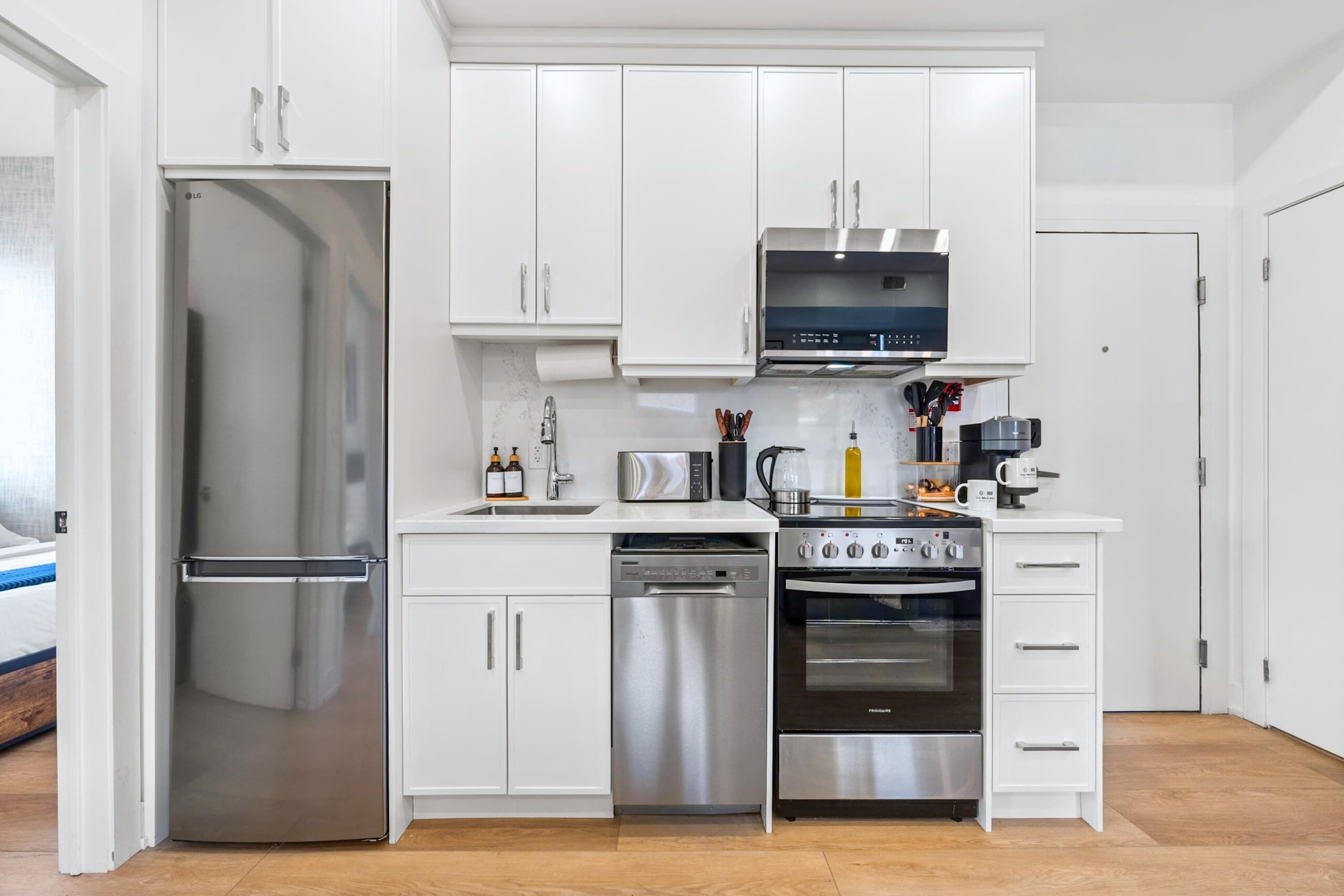 A modern kitchen with stainless steel appliances, white cabinetry, and a dishwasher.