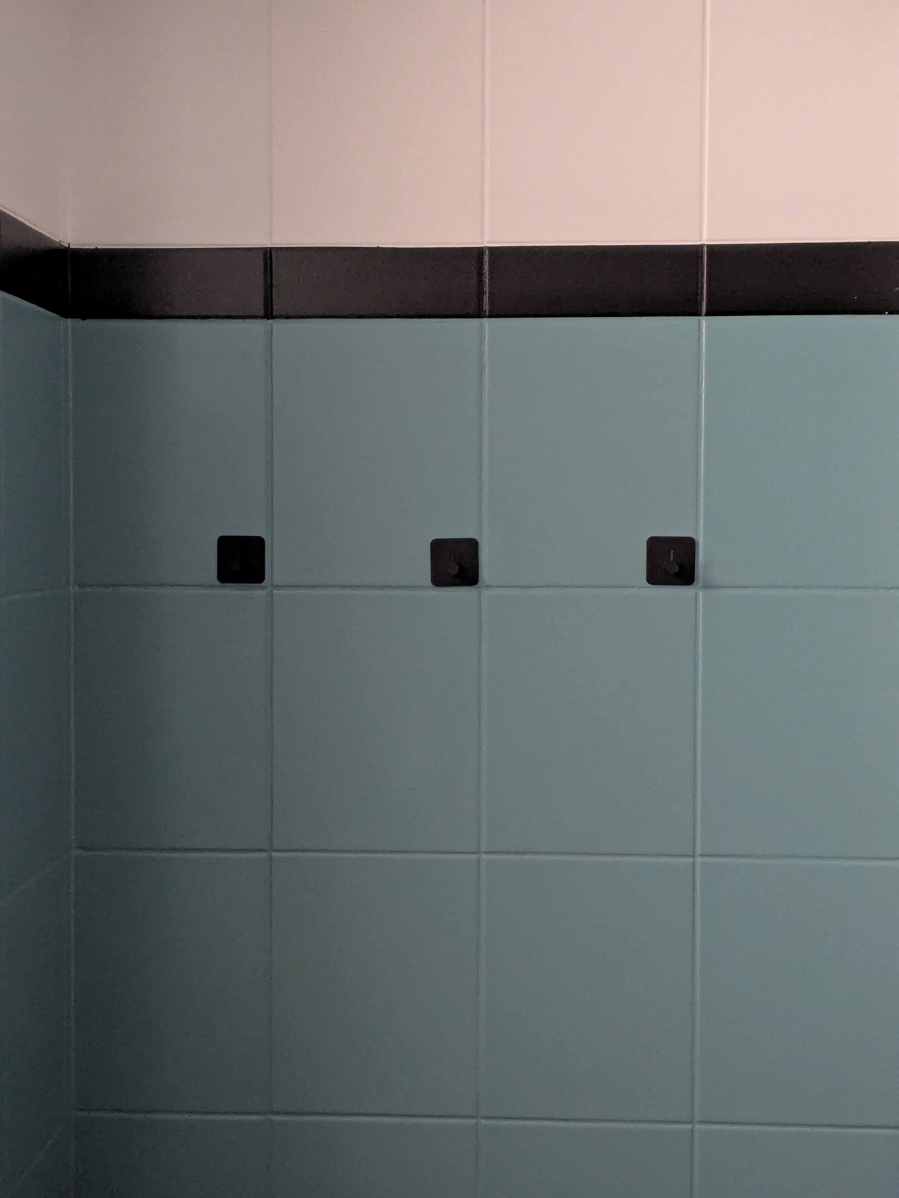A bathroom with teal tiles and black fixtures.
