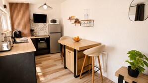 Una cocina moderna con encimera de madera, horno integrado, microondas y comedor con mesa de madera y taburetes de bar.