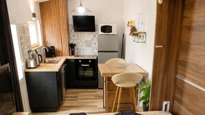 Habitación de hotel con cama, escritorio, silla, televisión y kitchenette.
