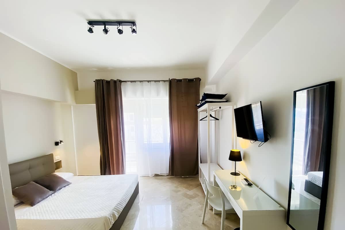 Ein Hotelzimmer mit Bett, Schreibtisch, Fernseher und Spiegel.