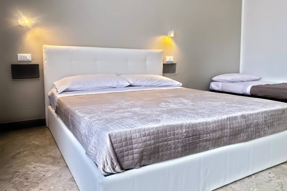Ein modernes Hotelzimmer mit einem großen Bett, zwei Nachttischen und Wandleuchten.