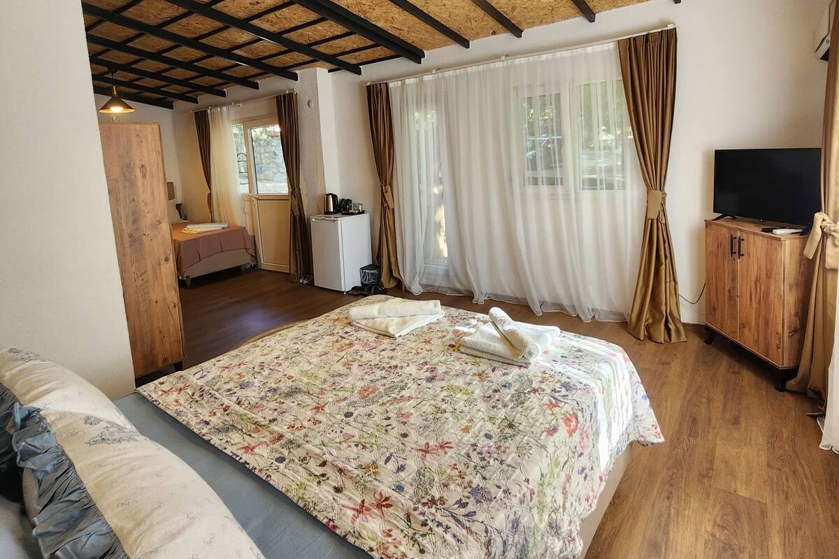 Un dormitorio con techo de madera, una cama con ropa de cama floral, un televisor y un armario de madera.