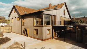 Une maison en bois avec un toit en pente, de grandes fenêtres et un balcon.