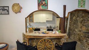 A kitchen with a stone wall, a wooden counter, and a large wheel chair.