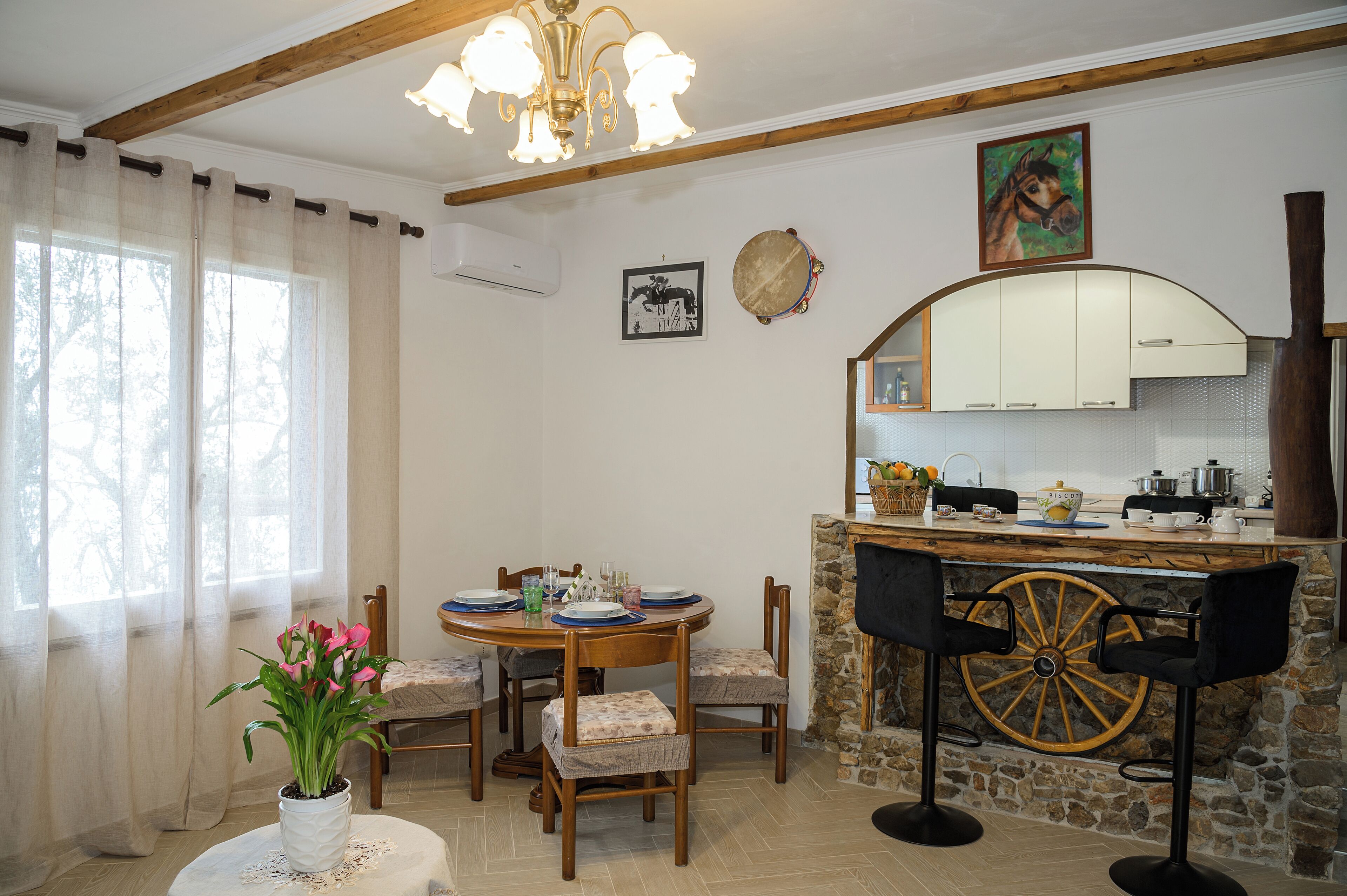 Un coin repas avec une table ronde, des chaises et une plante en pot. Il y a également un coin cuisine avec une cuisinière, un évier et des placards.