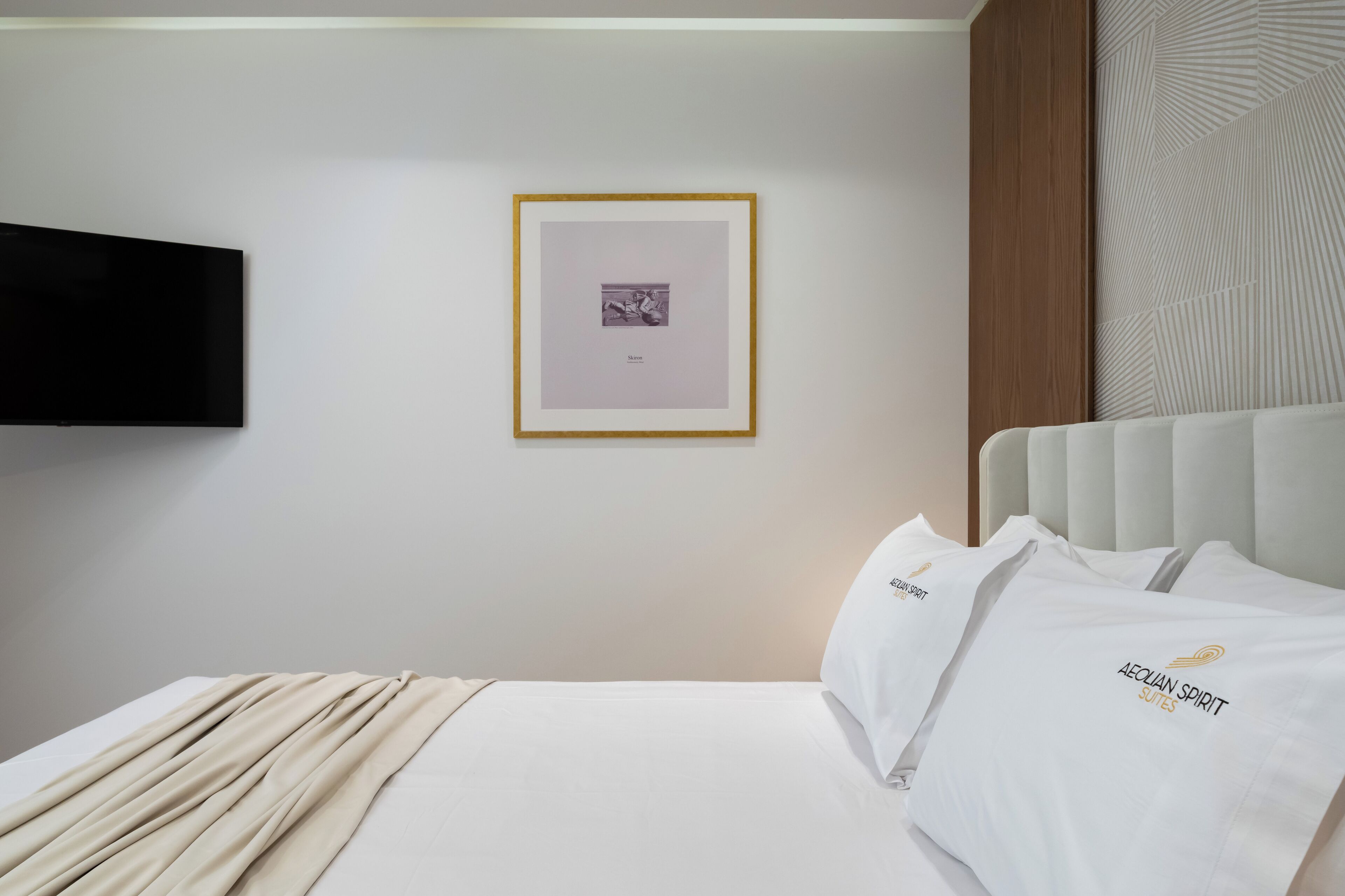 A hotel room with a bed, a framed picture on the wall, and a television mounted above it.