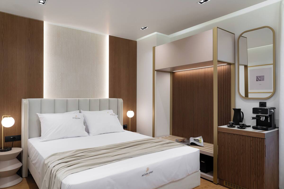 Une chambre d’hôtel moderne avec un grand lit, des lampes de chevet, une armoire en bois, une machine à café et un miroir.