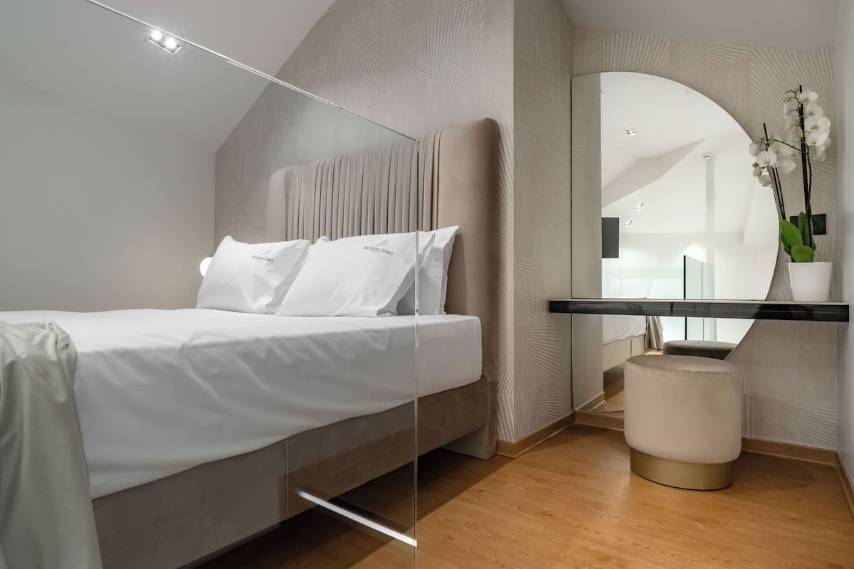Une chambre à coucher moderne avec un lit, une coiffeuse avec un miroir et un petit tabouret.