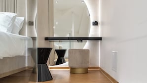 Une chambre d’hôtel moderne avec un grand miroir, un lit, un pouf rond et un escalier avec des marches en bois.