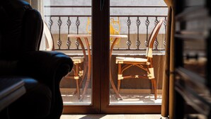 A room with a sliding glass door leading to an outdoor balcony with wicker furniture and a metal railing. - Hotel Perun (Budva)