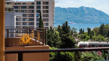 Een balkon met een decoratieve balustrade, uitzicht op een berg en gebouwen op de achtergrond.
