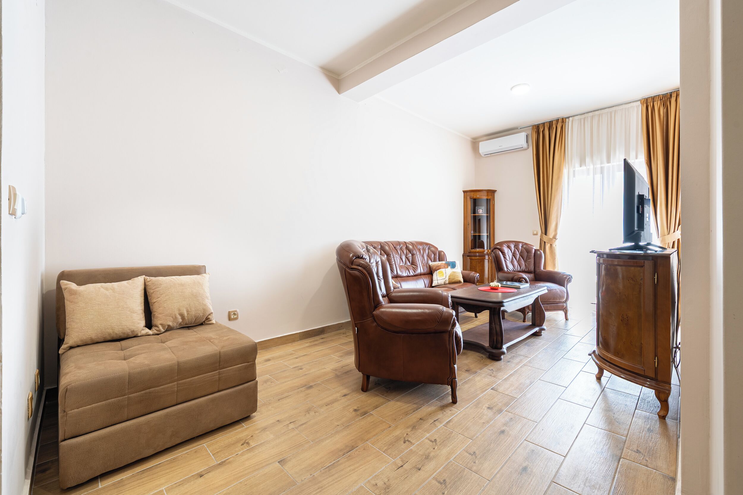 Ein Wohnzimmer mit Sofa, Sessel, Couchtisch und Schrank.