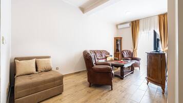 Ein Wohnzimmer mit Sofa, Sessel, Couchtisch und Schrank.