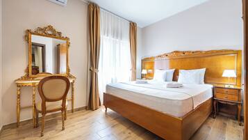 Une chambre d’hôtel avec un grand lit, un bureau en bois, une chaise, une table de chevet et un miroir.