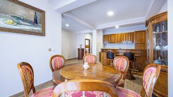 Un área de comedor con una mesa redonda de madera, seis sillas con tapicería estampada y un cuadro en la pared.