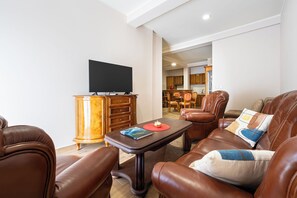 Una sala de estar con sofás de cuero, una mesa de centro, un televisor y un mueble de madera.