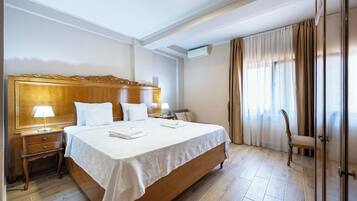 A hotel room with a large bed, bedside tables, a lamp, a chair, and a wardrobe.