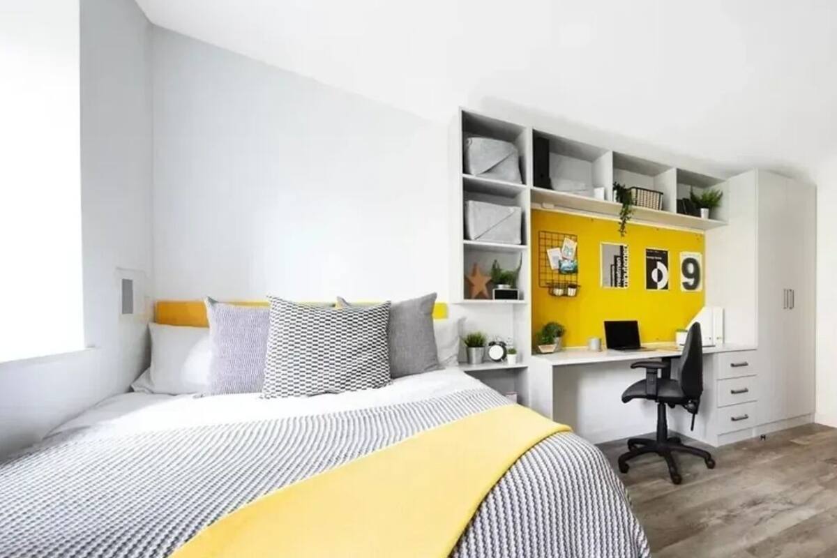 Une chambre à coucher comprenant un lit, un bureau et une étagère avec des rangements.