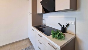 Et moderne køkken med et sort emfang, en vask og en bordplade med en plante og redskaber.