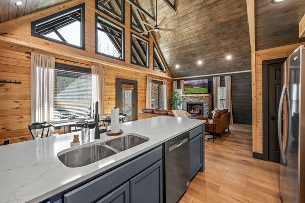 Una cocina moderna con una isla grande, electrodomésticos integrados y un comedor con vistas al exterior.