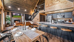 A spacious kitchen with a large island, a dining area with a wooden table set for four, and a cozy living area with a fireplace.