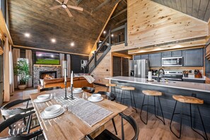 A spacious kitchen with a large island, a dining area with a wooden table set for four, and a cozy living area with a fireplace.
