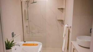 Une salle de bain moderne avec une baignoire aux lignes courbes, des toilettes et un lavabo.