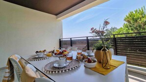 A balcony with a table set for breakfast, including fruits, pastries, and beverages.