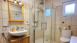 A modern bathroom with a glass shower enclosure, a sink with a mirror, and a toilet. - Friendly Home - Villa Verde - near Phantasialand/Cologne/Bonn (Bornheim)