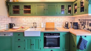 A kitchen with green cabinets, a white sink, a dishwasher, and an oven. - Friendly Home - Villa Verde - near Phantasialand/Cologne/Bonn (Bornheim)