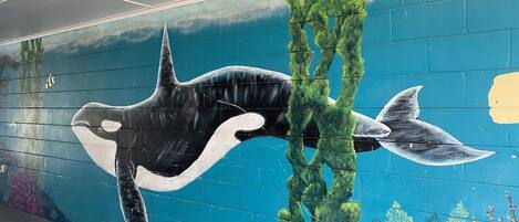 Un mural con una ballena y plantas marinas sobre una pared.