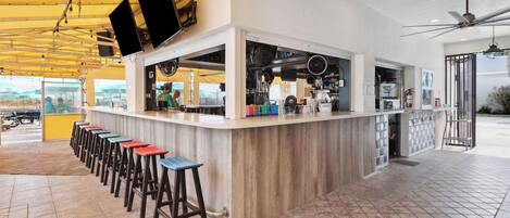 A bar area with stools, a counter, and a ceiling fan.