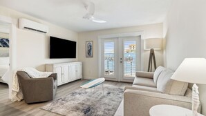 Un salon moderne avec un téléviseur à écran plat, un canapé, une table basse et une lampe.