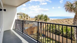 A balcony with a view of the beach and palm trees. - Indulge in an Oceanfront King with Nearby Dining and Attractions, Pet Friendly (Neptune Beach)