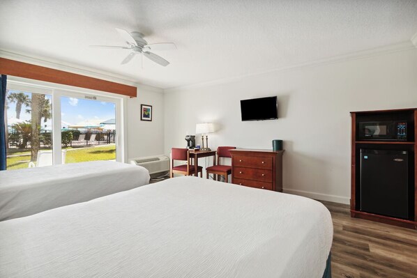 Habitación de hotel con dos camas, un escritorio con sillas, televisión, microondas y vistas al exterior.