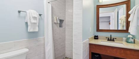 A bathroom with a shower, toilet, and sink.