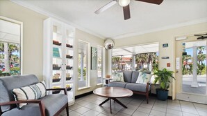 A lobby with a grey sofa, a wooden coffee table, and a bookshelf with various items. - Explore Local Gems from a Relaxing Beachfront Room with Outdoor Swimming Pool (Neptune Beach)
