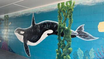 A mural of a whale and sea plants on a wall.