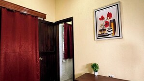 A room with a wooden dining table, white chairs, a red curtain, and a framed picture on the wall. - Hotel Maya Magic Petén (Flores)