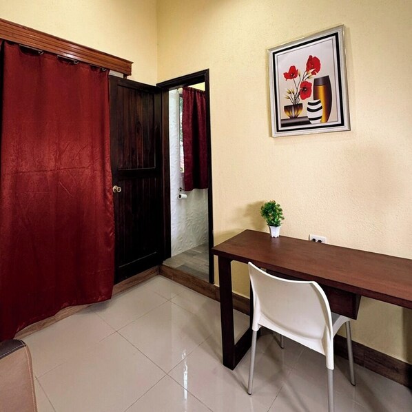 A room with a wooden dining table, white chairs, a red curtain, and a framed picture on the wall. - Hotel Maya Magic Petén (Flores)