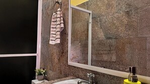 A bathroom with a granite countertop, a white sink, a mirror, and a towel hanging on a towel rack. - Hotel Maya Magic Petén (Flores)