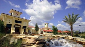Un hotel con un patio central que presenta una cascada, palmeras y una torre del reloj.