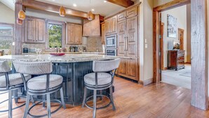 A spacious kitchen with wooden cabinets, a large island with bar stools, and a view of the outdoors.