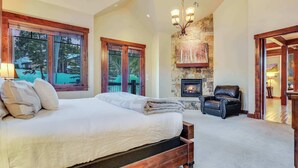 A spacious bedroom with a large bed, a fireplace, and a view of the outdoors.