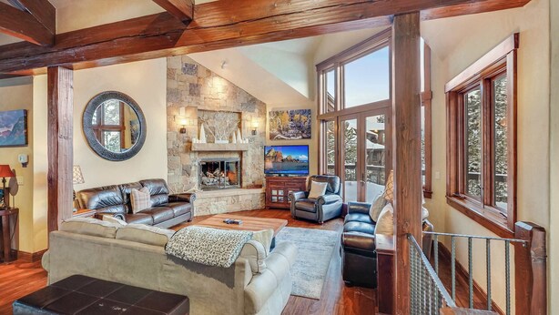 A spacious living room with a fireplace, leather sofas, and a stone wall.