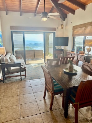 Relax in a spacious living area with a high ceiling and large sliding glass door leading to a balcony with mountain views.